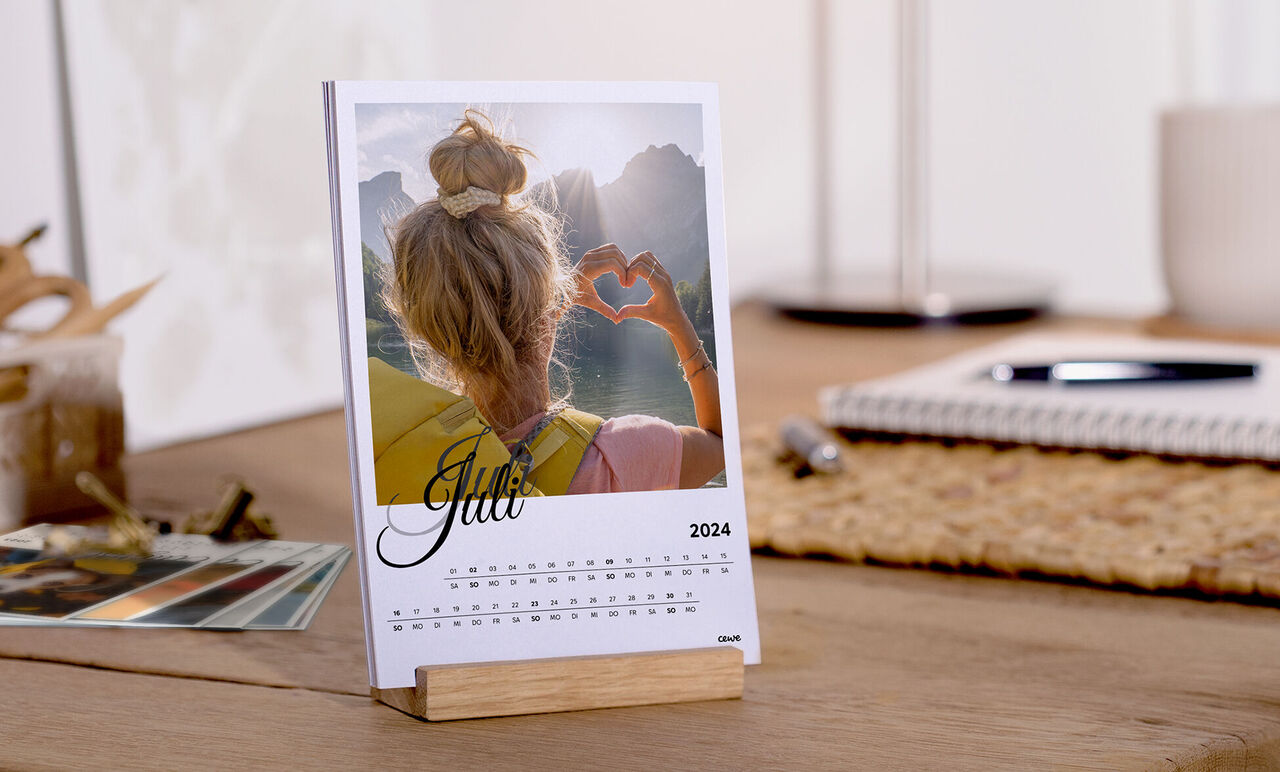 Gratis bordkalender for juni 2025 med et kærligt designet foto af en person, der former et hjerte med hænderne.