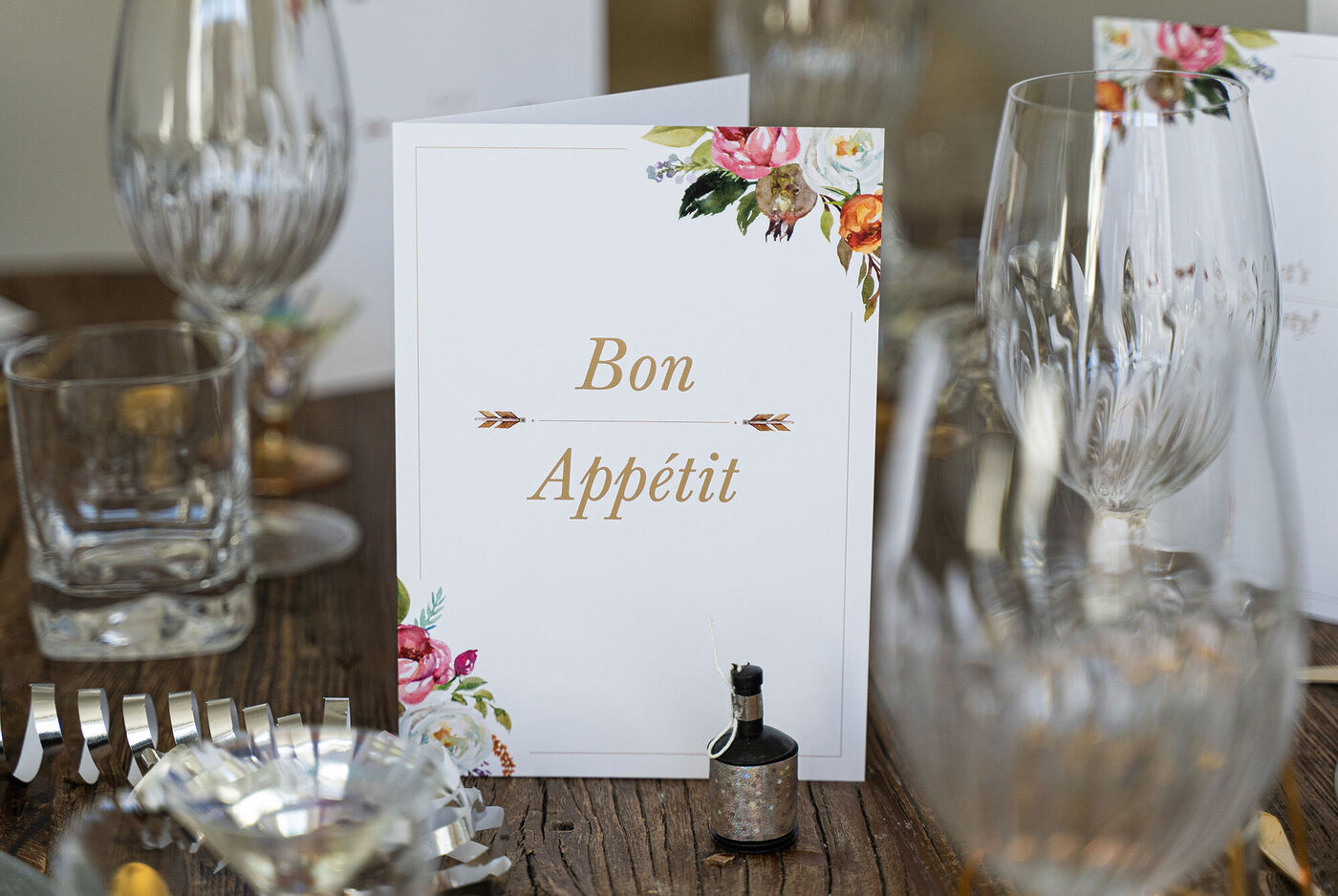 Et bord med festlig dekoration, hvor et "Bon Appétit" kort står i elegant skrift