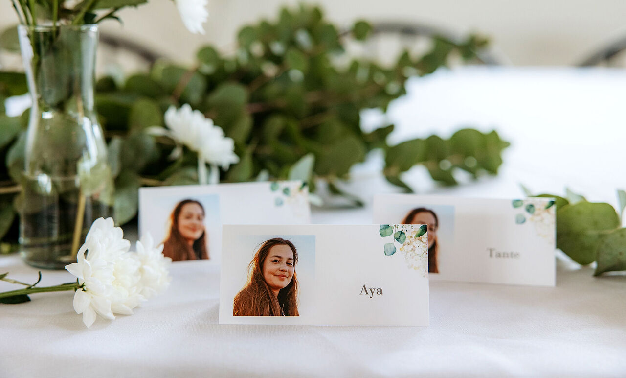 Pladskort til gæster ved en fest, med blomsterdekoration.