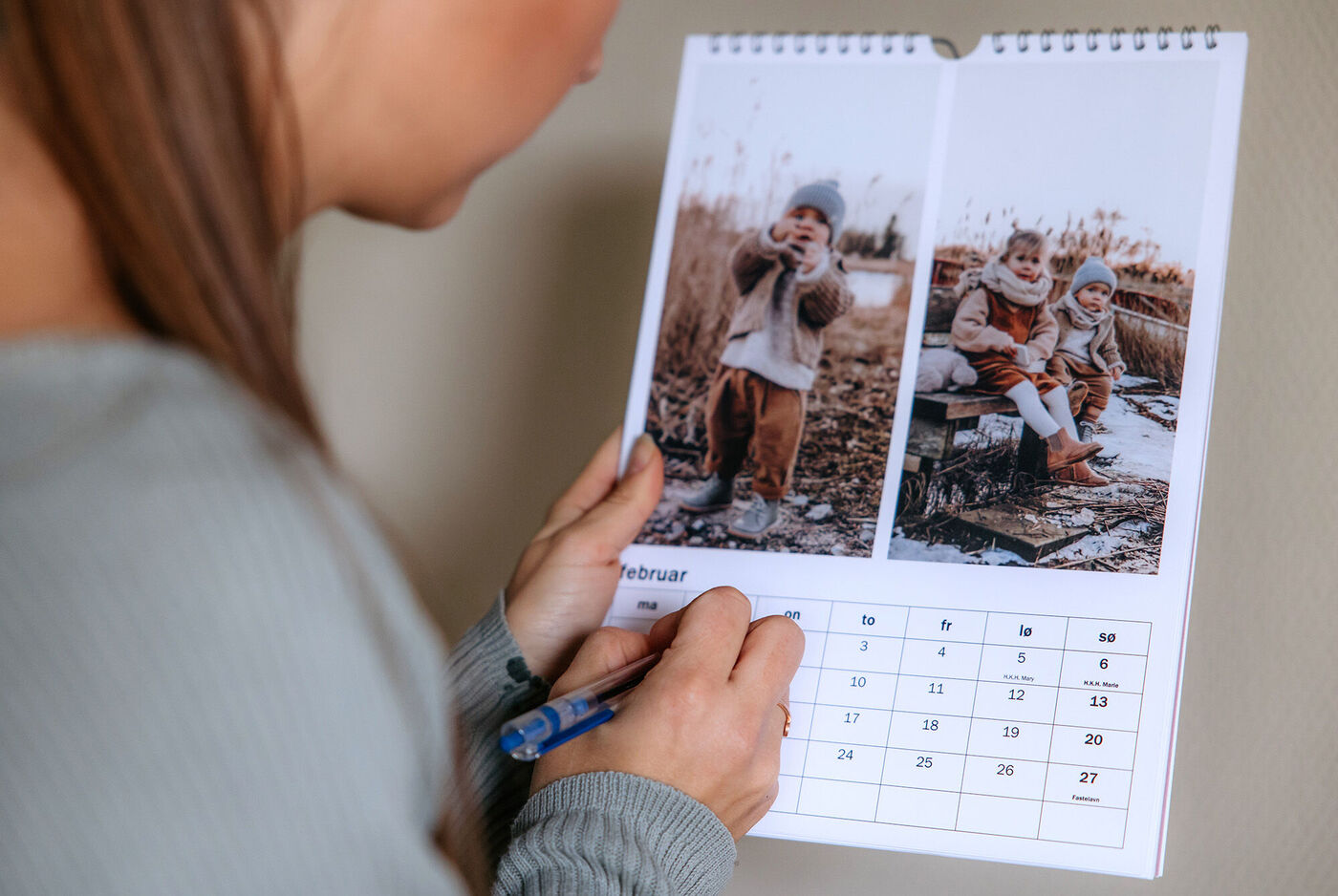 Person skriver i en fotokalender med billeder af børn om vinteren