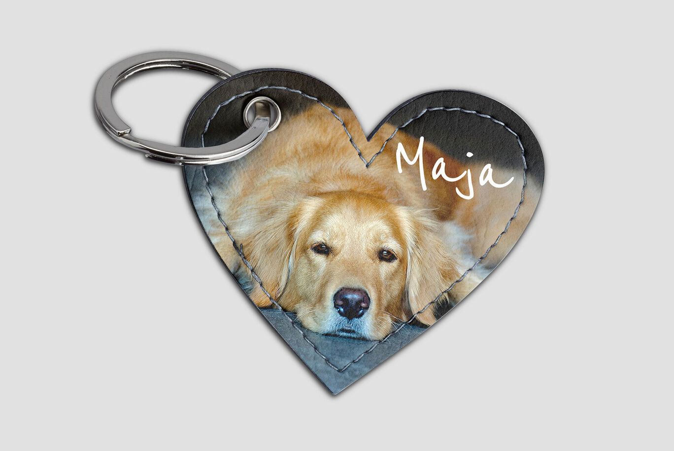 En hjerteformet nøgleanhænger med billede af en golden retriever ved navn Maja, der ligger afslappet.