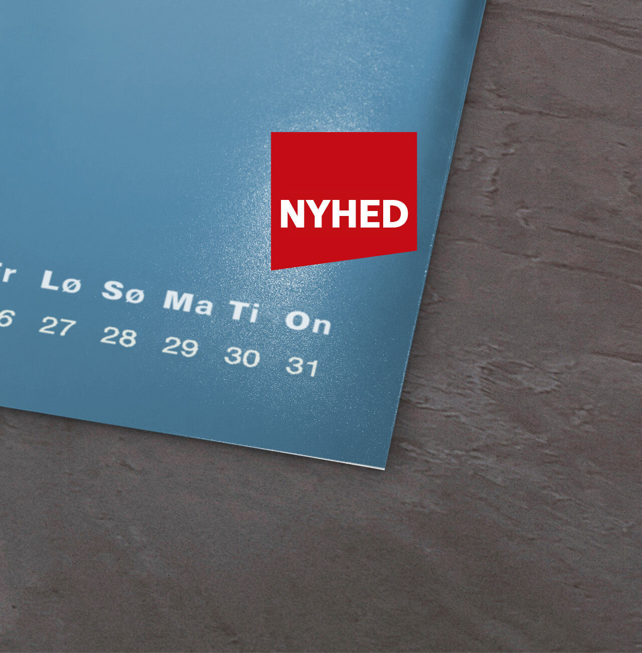 Kalenderblad med blå baggrund og rød klistermærke 'NYHED' i hjørnet