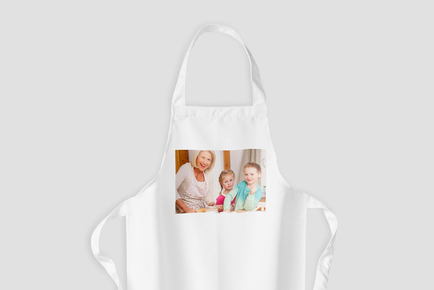 En hvid forkæde med billede af to smilede børn. Forkæden symboliserer kreative madlavningsmomenter.