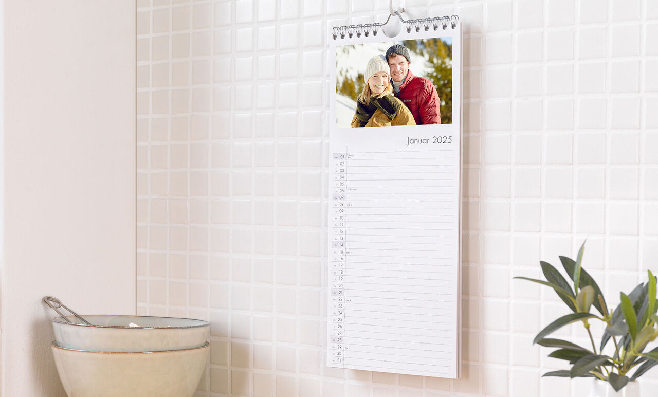 CEWE fotokalender med smilende par i januar 2025 på et køkkenskab.