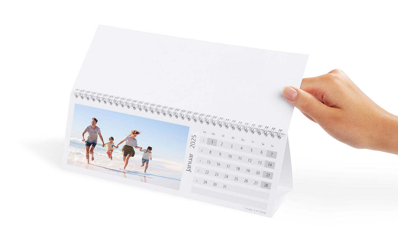 En kalender holdes, i baggrunden en glad familie på stranden.