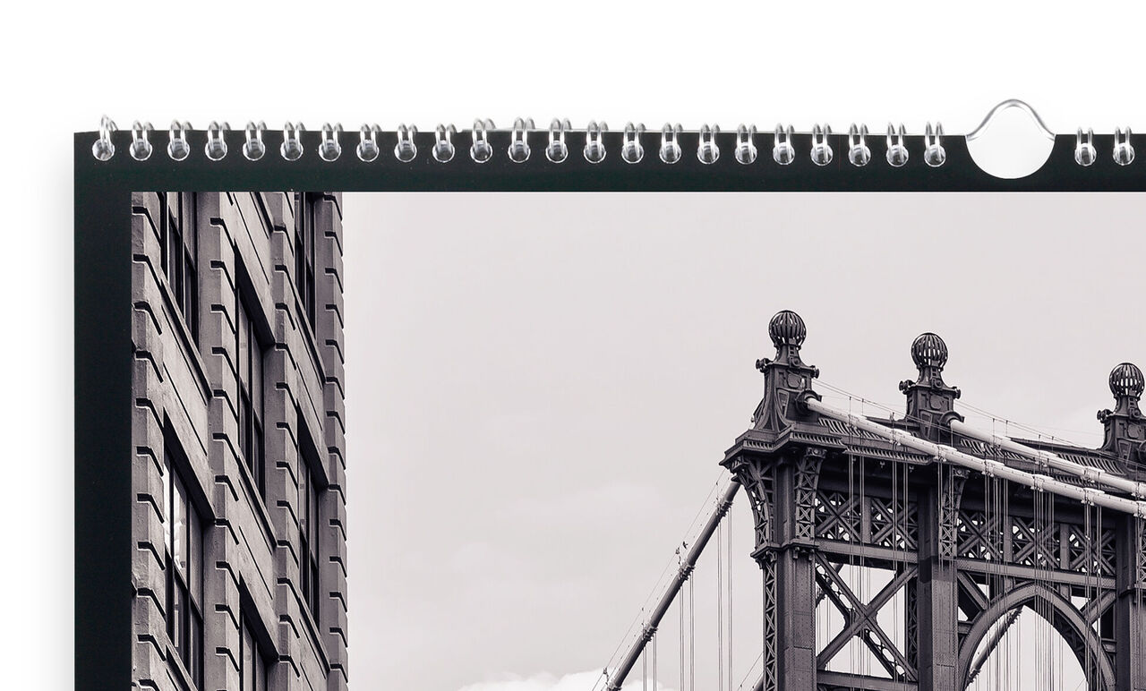 En kvalitets CEWE fotokalender viser et sort-hvidt foto af Brooklyn Bridge med en nærliggende bygning foran.