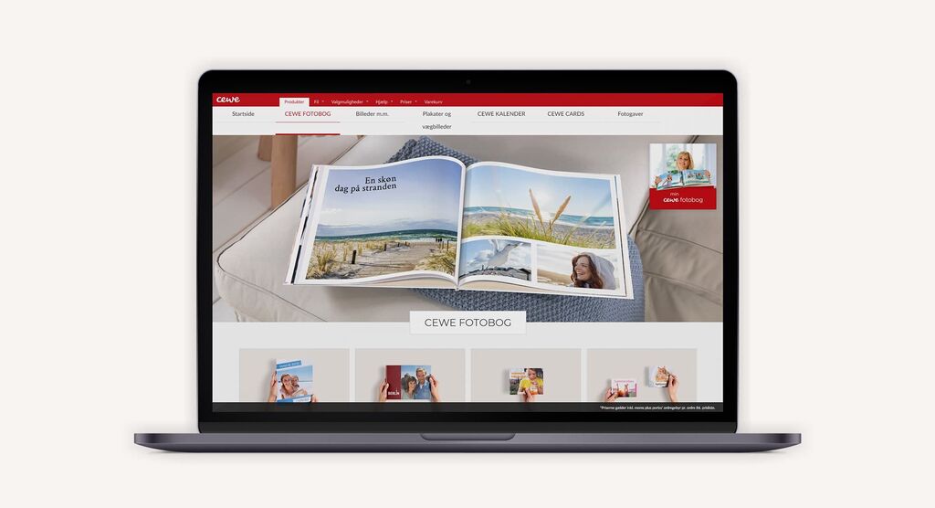 En person bladrer gennem åben CEWE FOTOBOG med billeder fra ferie og smukke landskaber på en laptop.