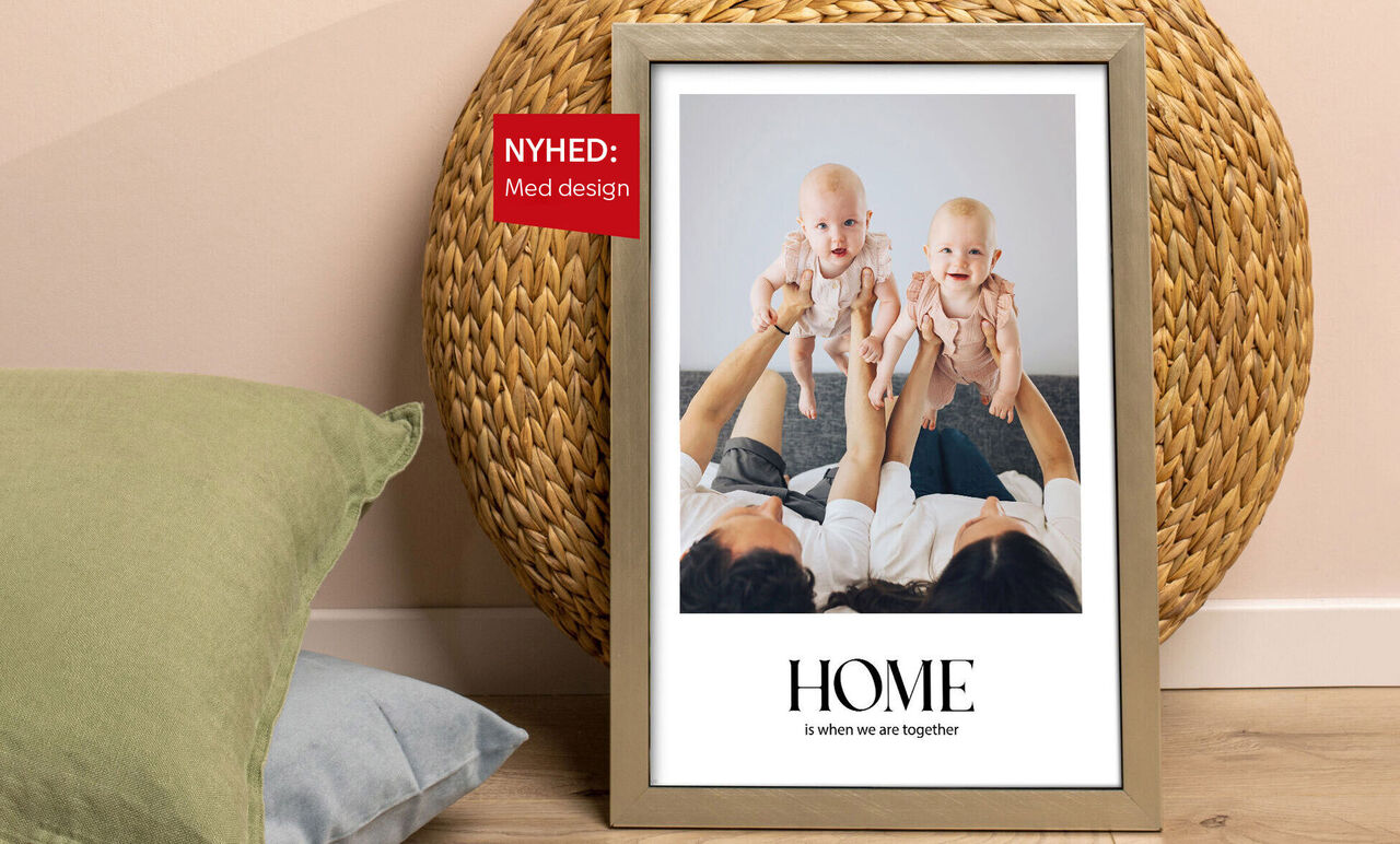 Familie holder to babyer med en billedramme i baggrunden.