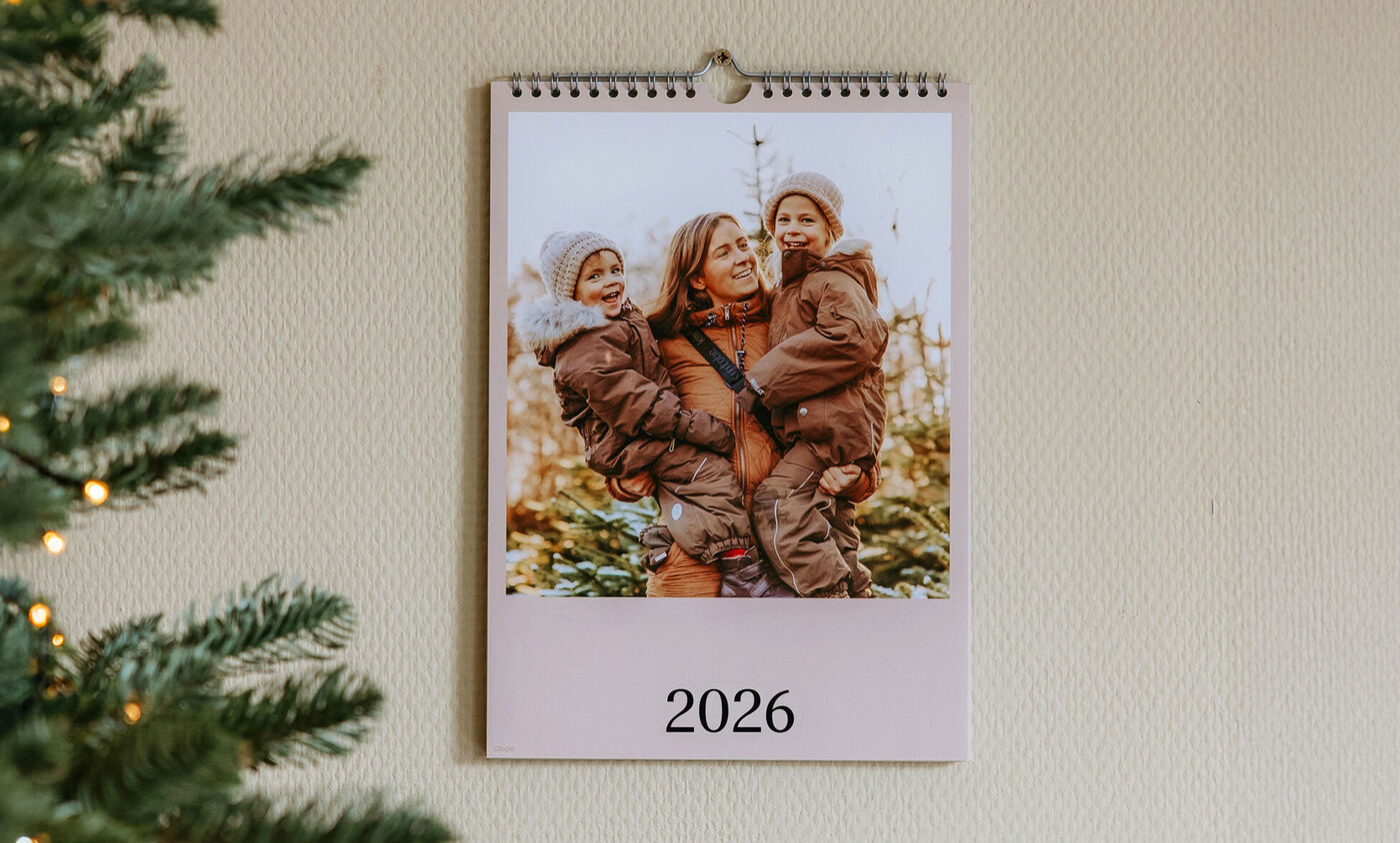 En vægkalender viser en kærlig familietilstand med børn udendørs.