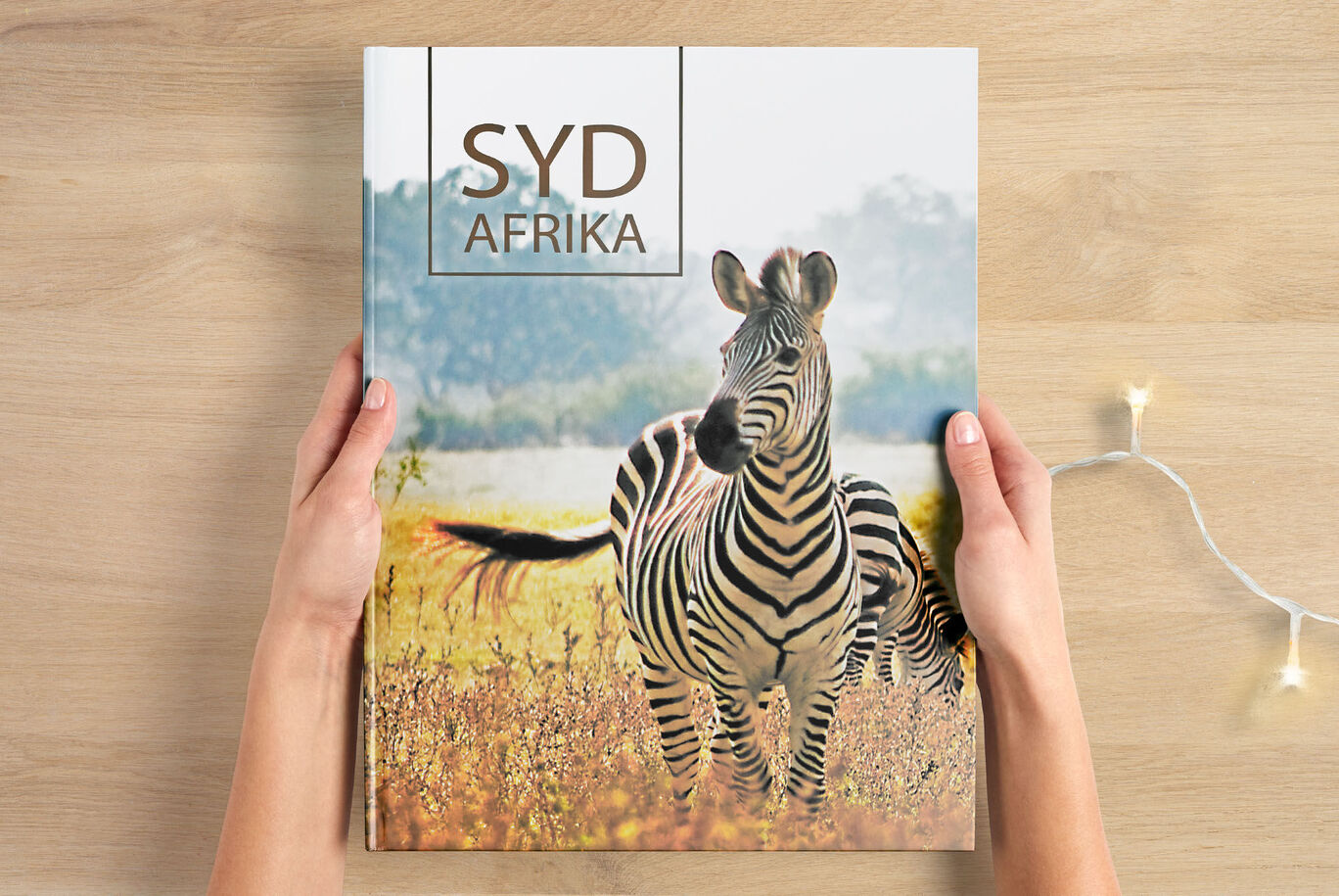 En person holder et CEWE fotoalbum med zebra på forsiden