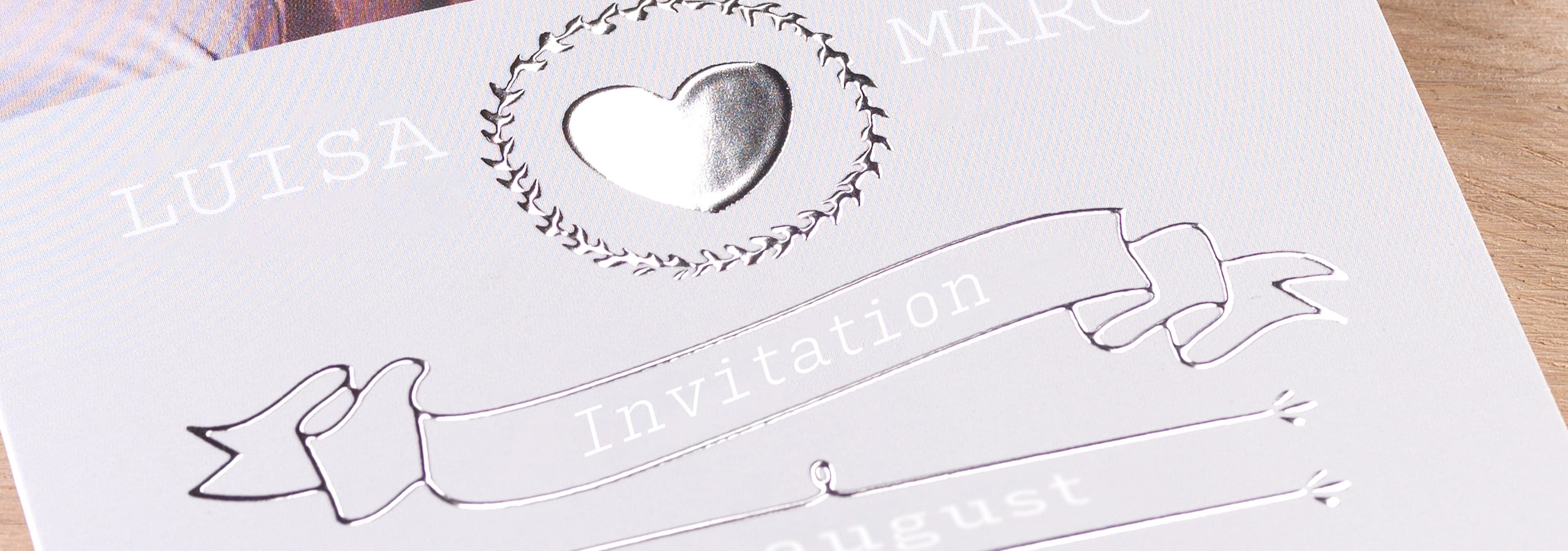 Elegant design af invitation med hjerteformet detalje omgivet af blomsterkrans.