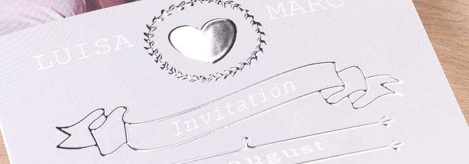 Elegant design af invitation med hjerteformet detalje omgivet af blomsterkrans.