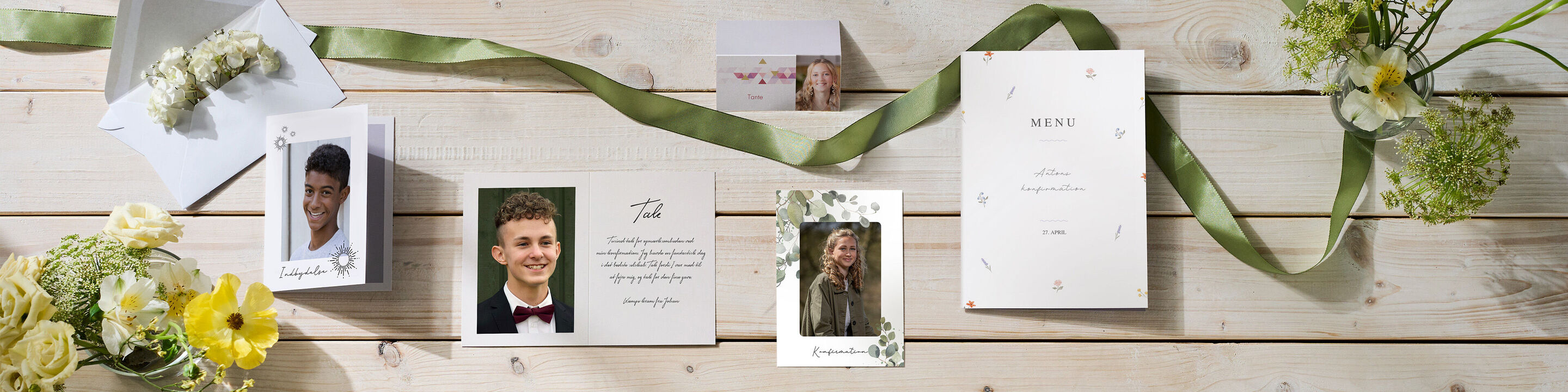 Et varmt udvalg af CEWE kort og et CEWE fotoalbum på et træbord, omgivet af blomster