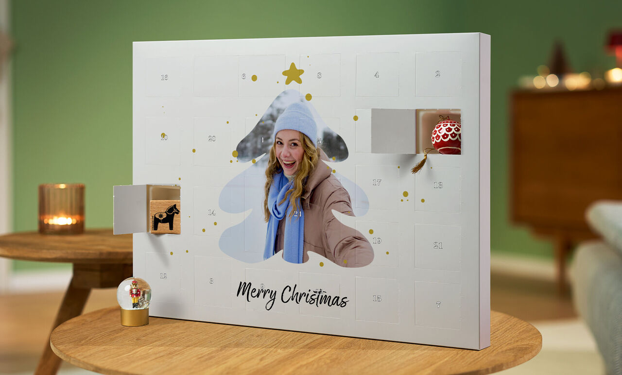 En åben julekalender formet som et juletræ med gaver og teksten 'Merry Christmas'