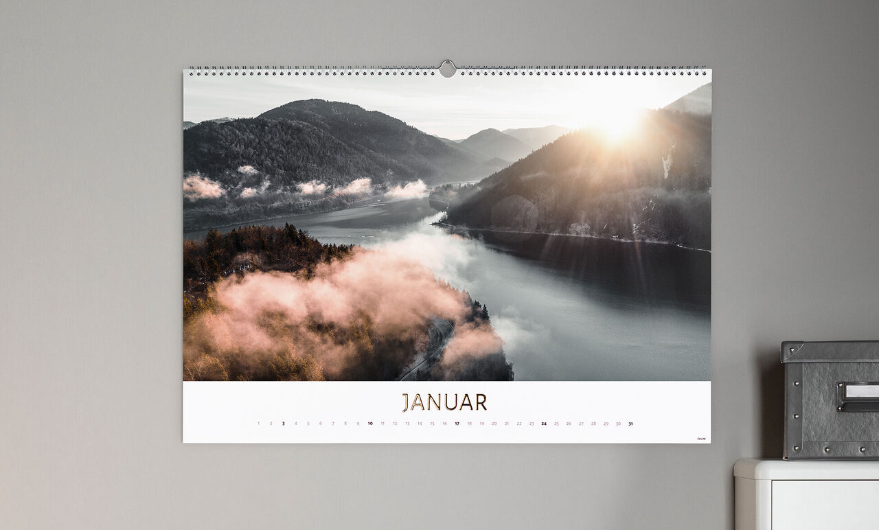 En CEWE fotokalender viser udsigten til en flod og bjerge i januar med blødt sollys.