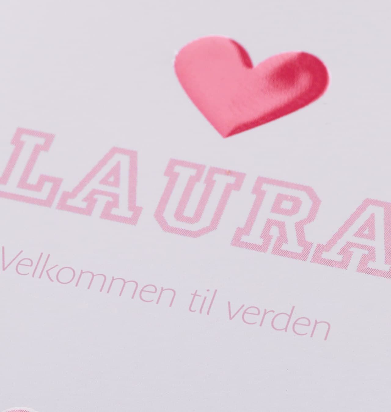Et hjerteformet symbol over navnet 'LAURA' på et kort, der siger velkommen.