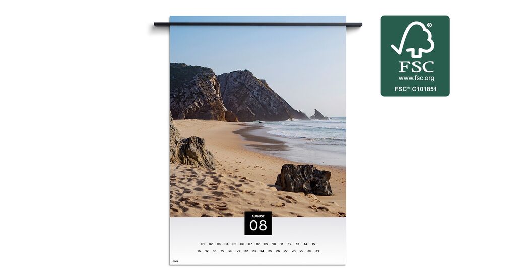 Strandlandskab med klipper og blide bølger under en blå himmel i en kalender for august.