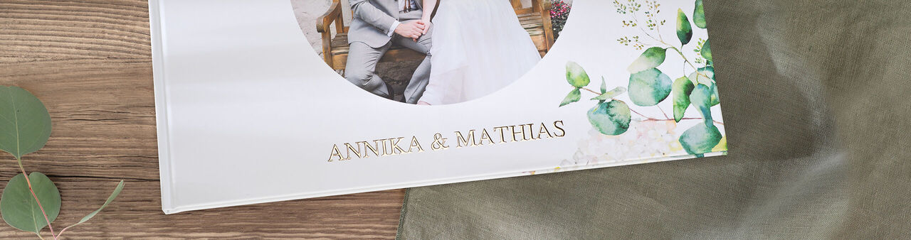En elegant CEWE fotobog med navnet "Annika & Matthias" og et blomsterdesign.