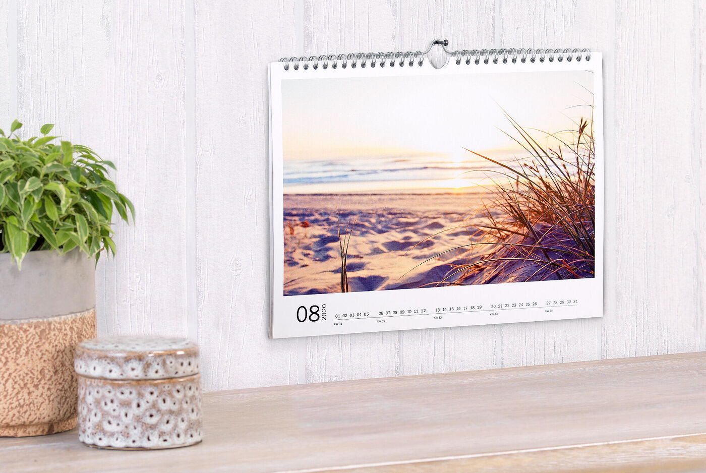 En smuk kalender med en solnedgang ved stranden og bløde græs i forgrunden.
