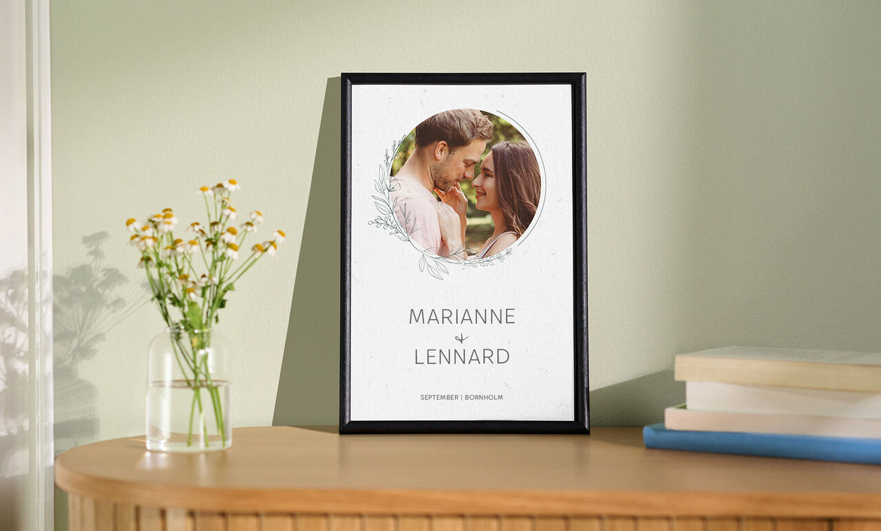 En plantet ramme med navnene Marianne og Lennard, omgivet af blomstrende planter.