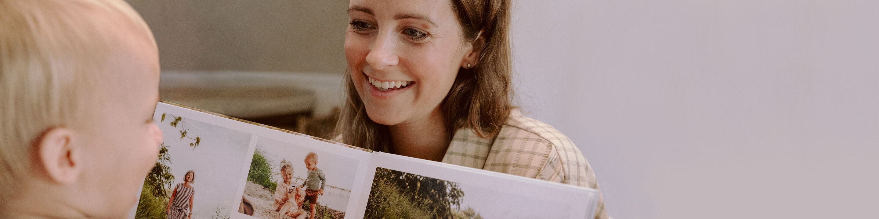 Et barn viser stolt en CEWE FOTOBOG med farverige minder.
