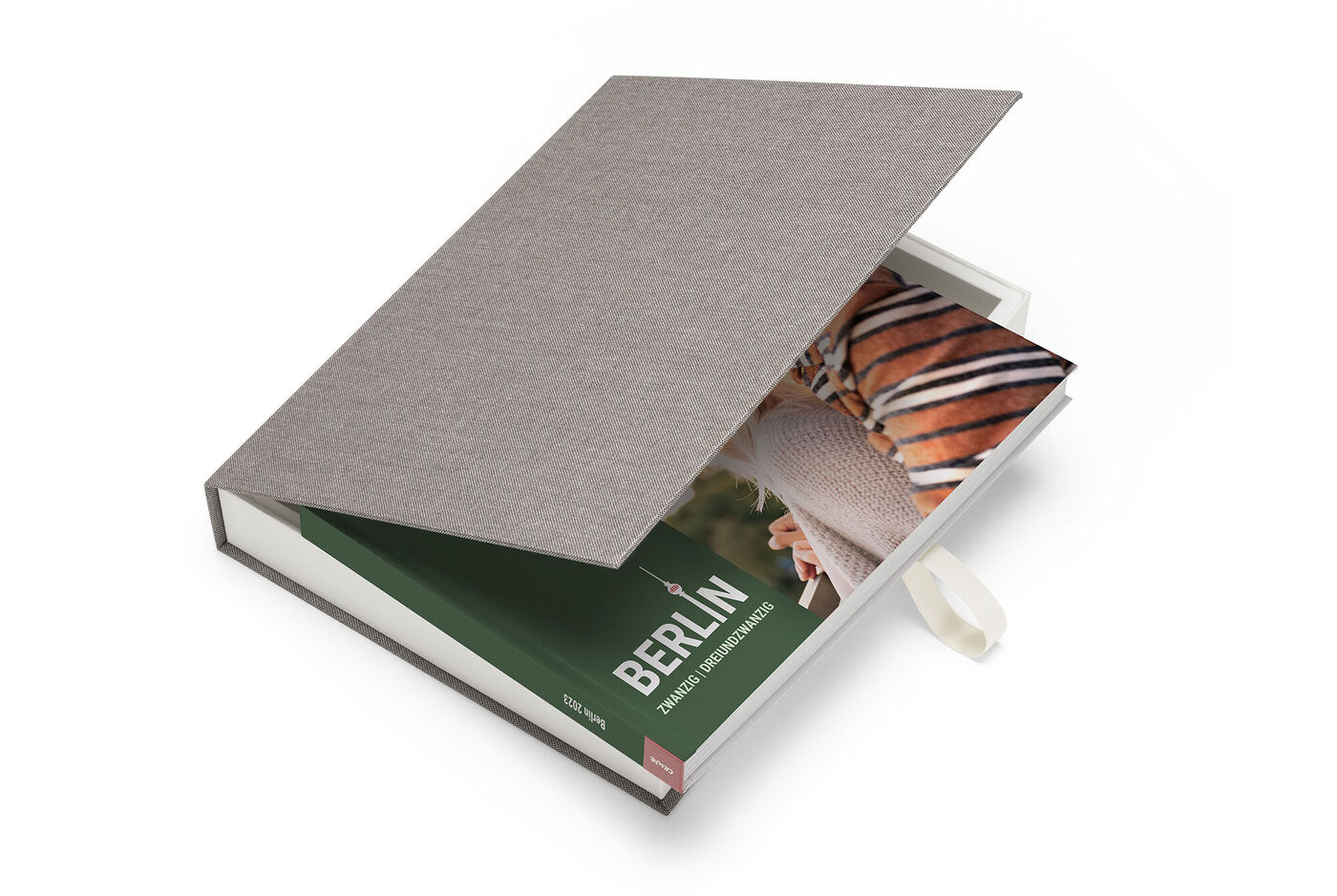 En åben CEWE FOTOBOK med et billede af Berlin og gråt stofomslag.