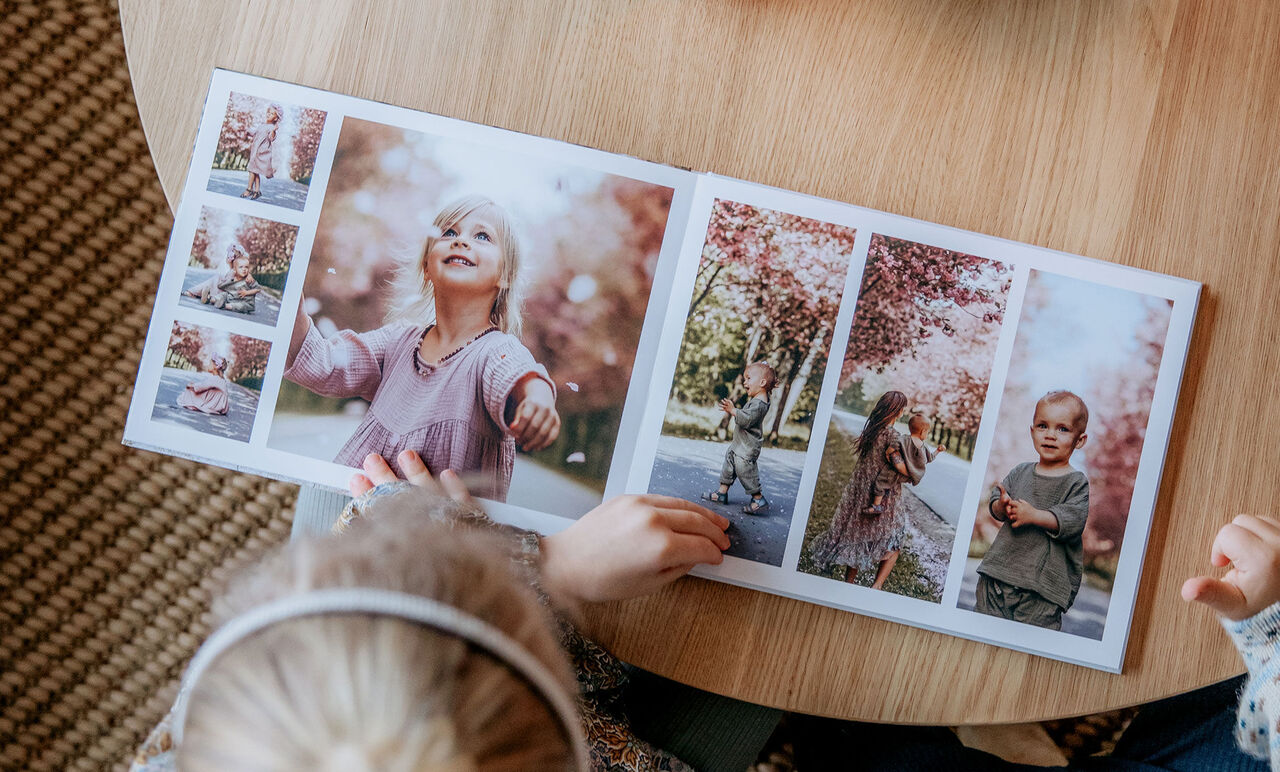 Et barn blader i en CEWE fotobog med familieminder udendørs.