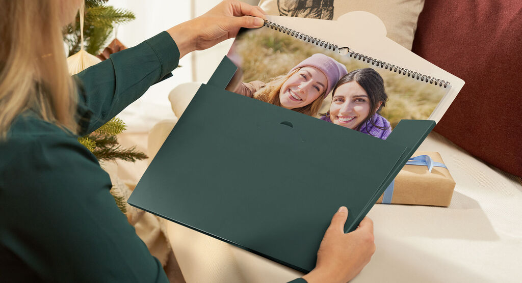 Person holder en fotokalender med billeder fra lykkelige øjeblikke.