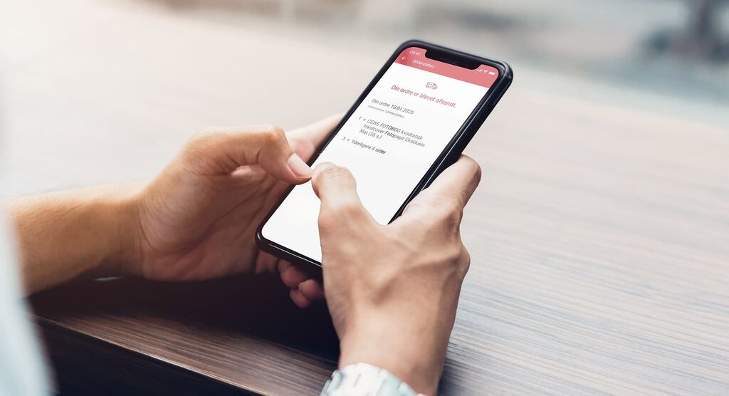 En person holder en smartphone og ser på en app med en liste.