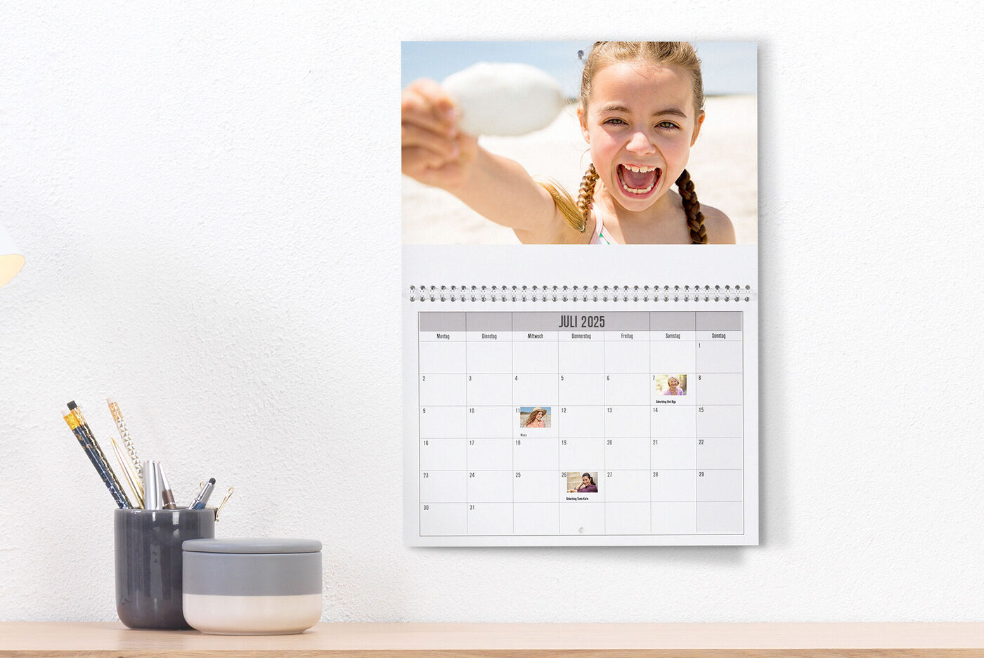En person holder en ske på stranden foran en kalender.