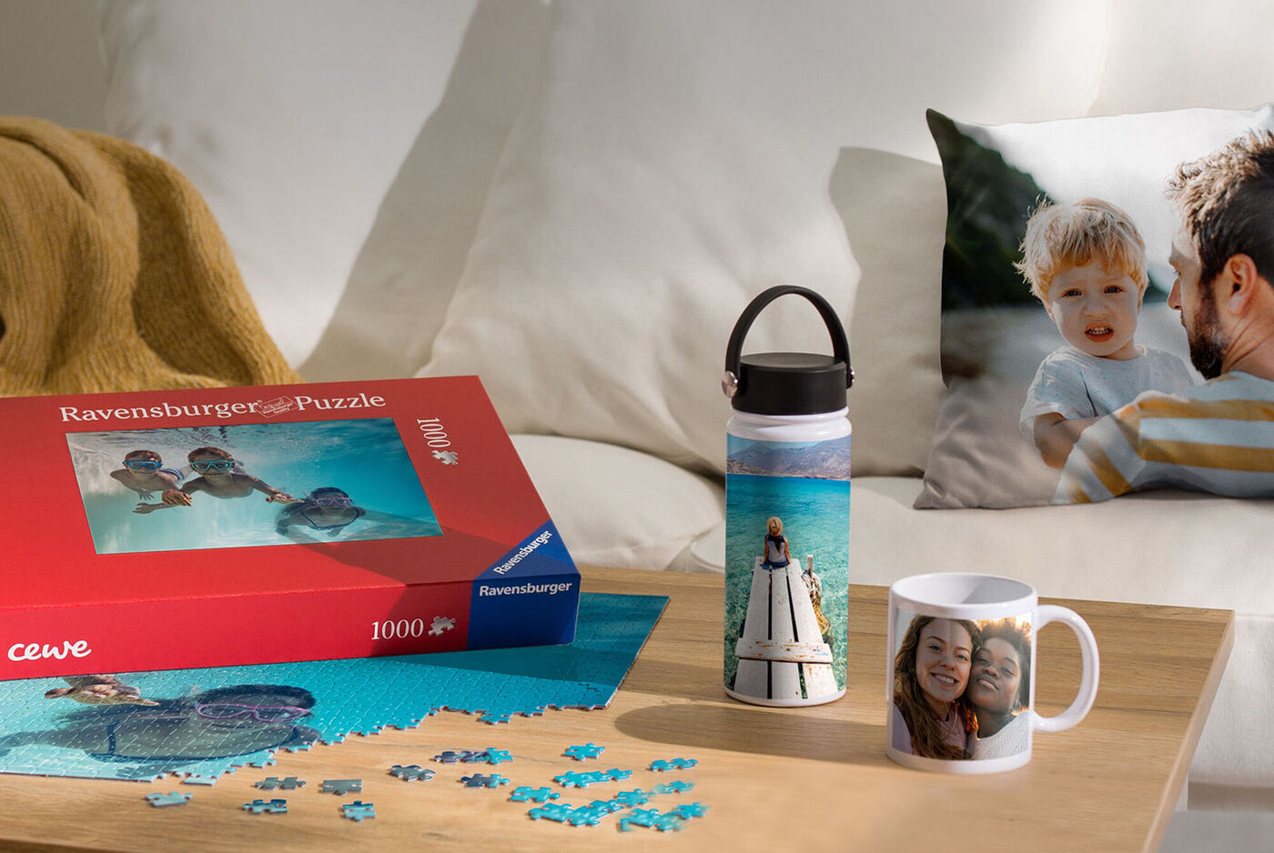En smuk bord med et Ravensburger puslespil, en personlig drikkeflaske og en pudebetræk med et billede.