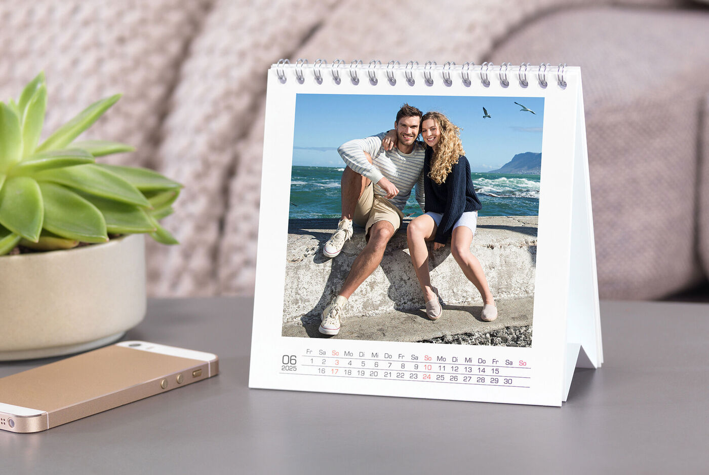 Et par poserer foran en kystlandskab i en bordkalender.