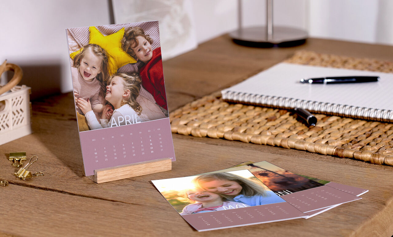 En farverig bord med en CEWE fotokalender, billeder af glade øjeblikke og søde minder.
