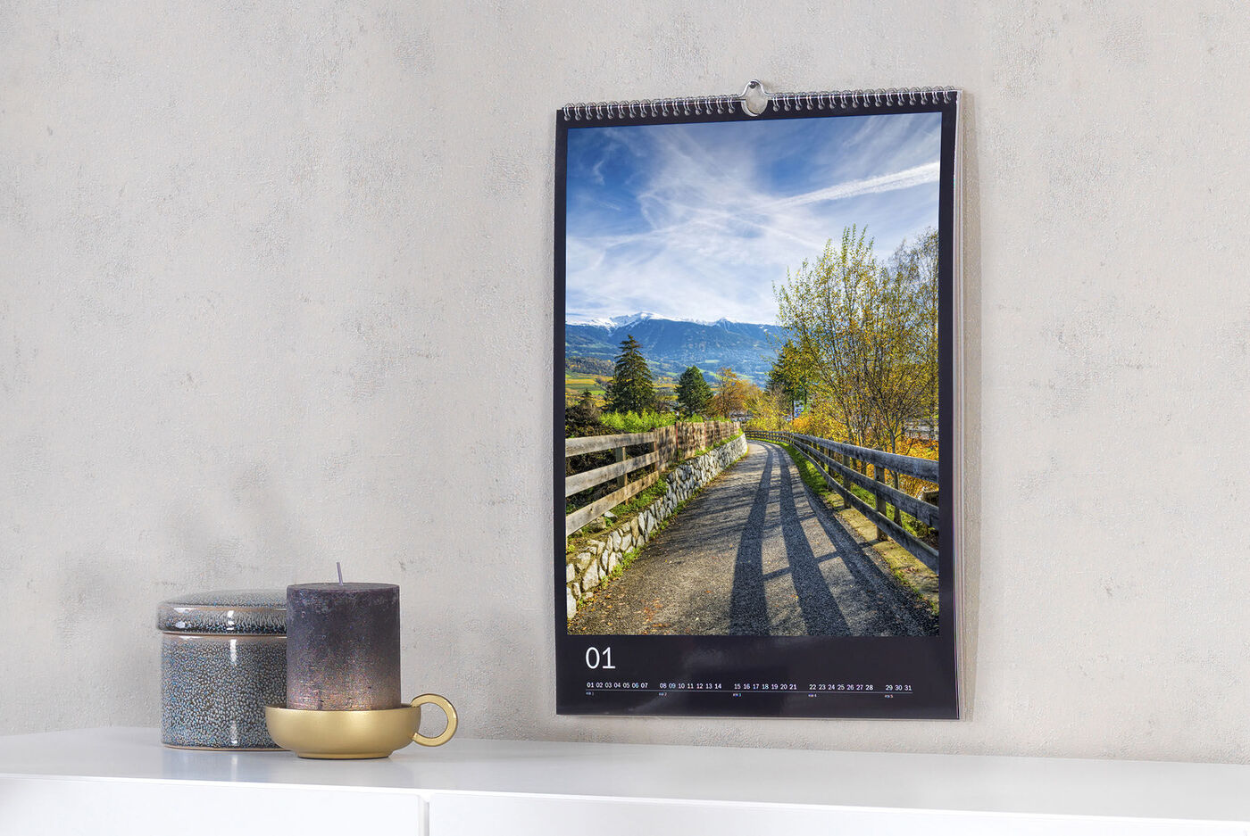 En smuk fotokalender hænger på væggen med billede af en sti i naturen.