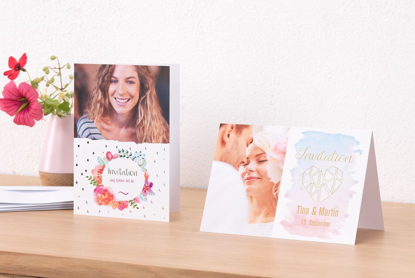 To vidunderlige indbydelseskort med florale motiver på et bord