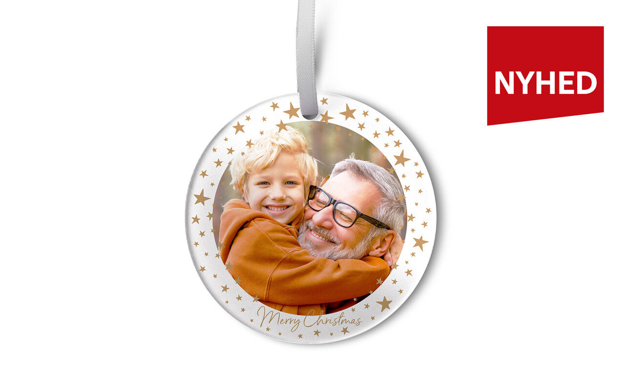 En juleanhænger viser en kærlig omfavnelse. Kanten har gyldne stjerner. Teksten 'Merry Christmas' er synlig.