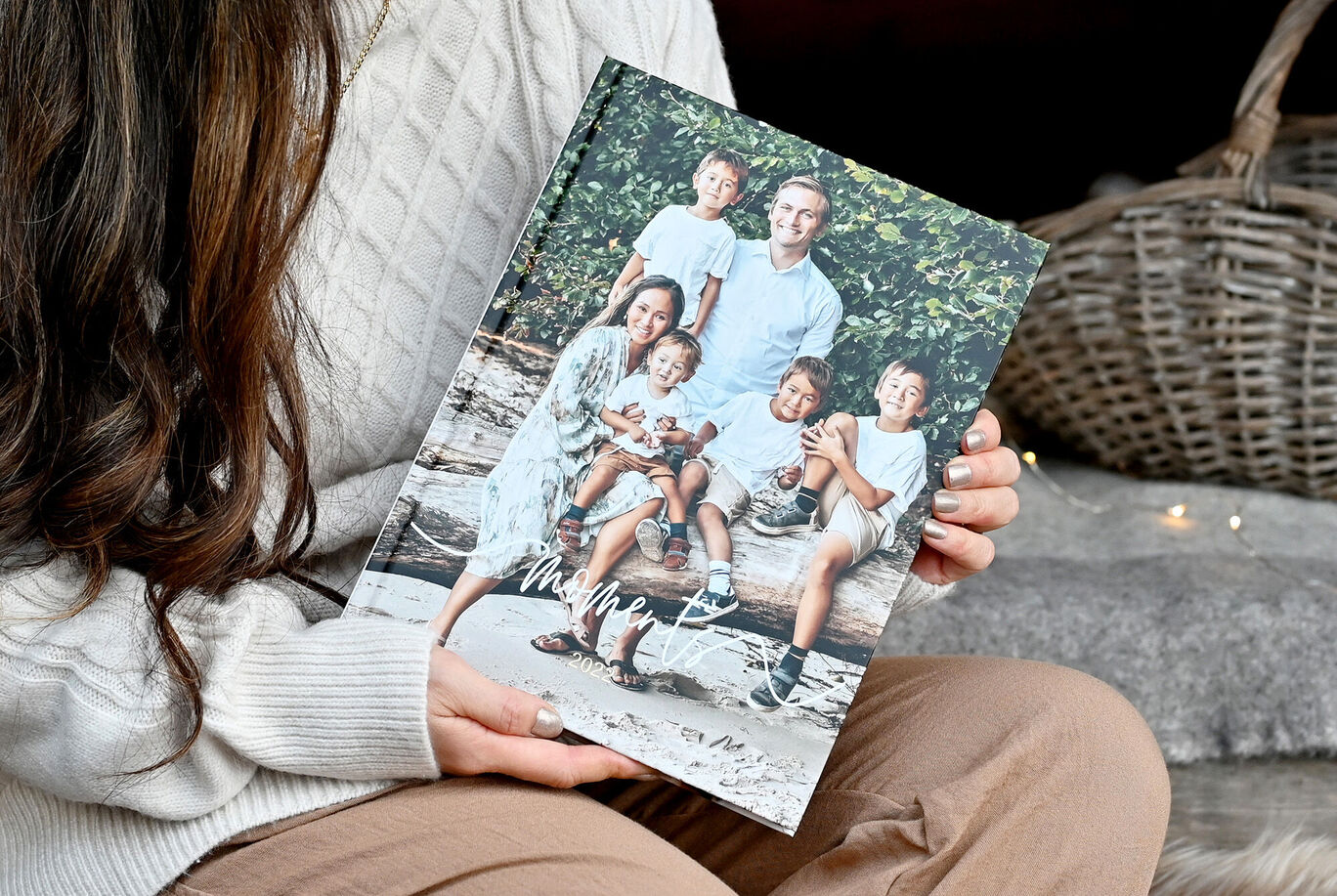 En person holder kærligt en CEWE fotobog med familiebilleder på et smukt sted i naturen.