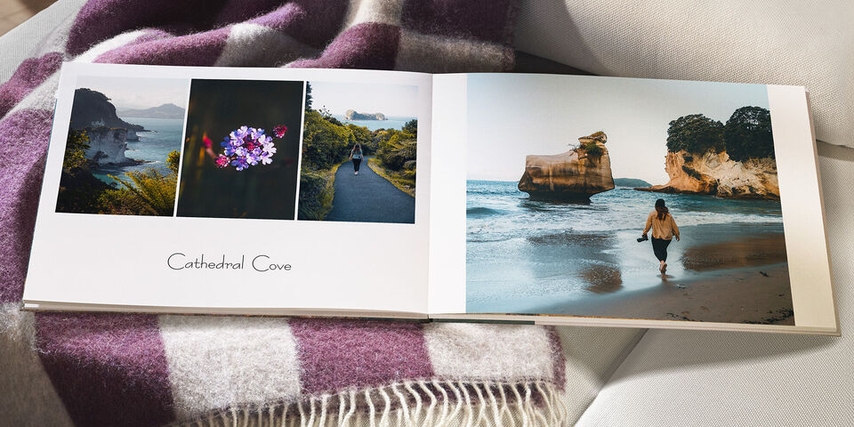 En åben fotobog med minder fra Cathedral Cove. Til venstre er tre billeder: blomstrende blomster, en vandresti og en kystlandskab. Til højre er en person, der går langs stranden.