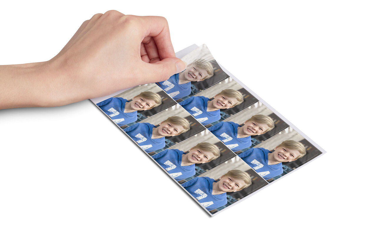 En hånd viser fotoaftryk af en dreng i blå tøj.